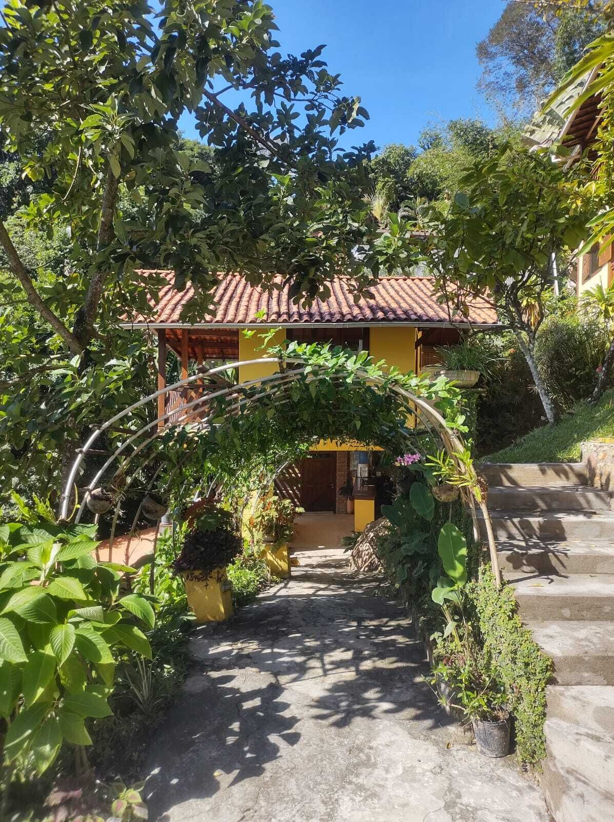 A pathway leading to a building with a tiled roof, surrounded by lush greenery and a stone staircase.