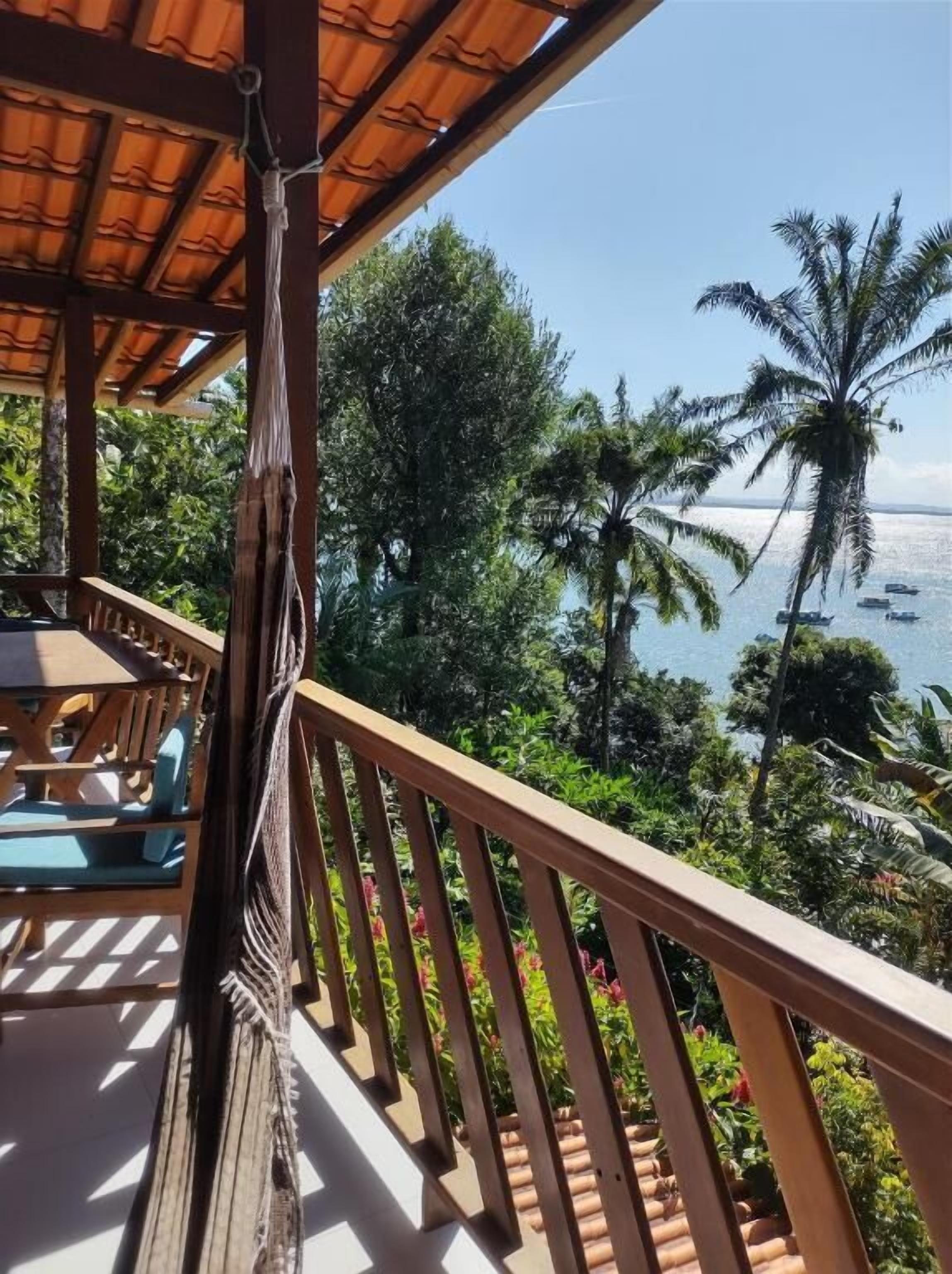 A wooden deck with a view of the ocean and palm trees.