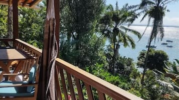Una terraza de madera con vista al océano y palmeras.
