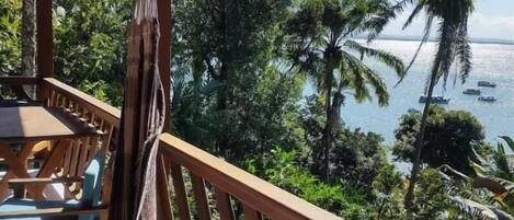 A wooden deck with a view of the ocean and palm trees.