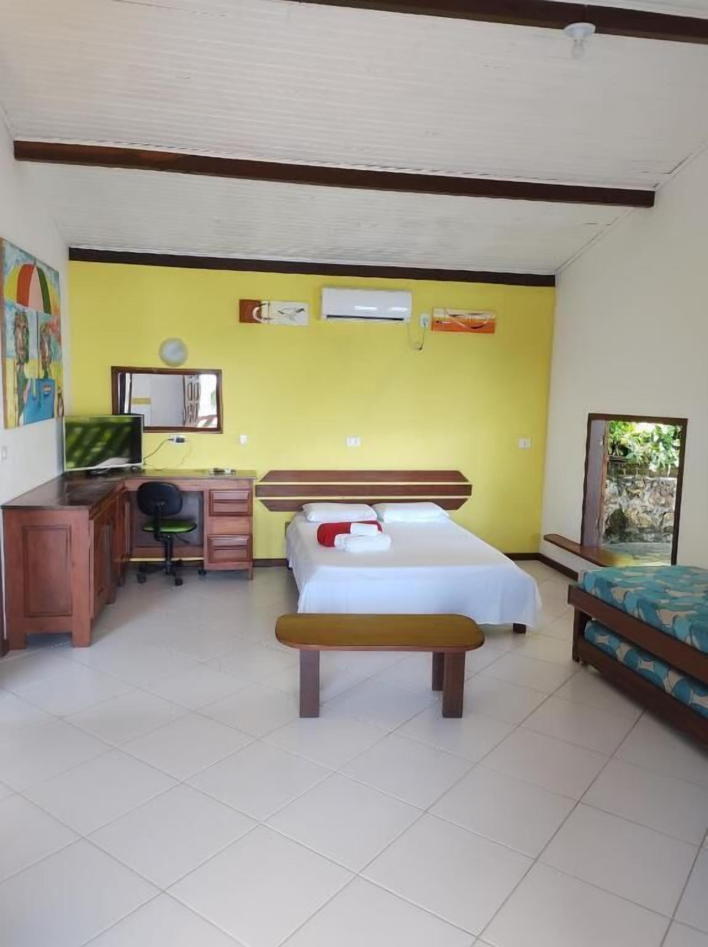 Un dormitorio con cama, escritorio, silla y banqueta.