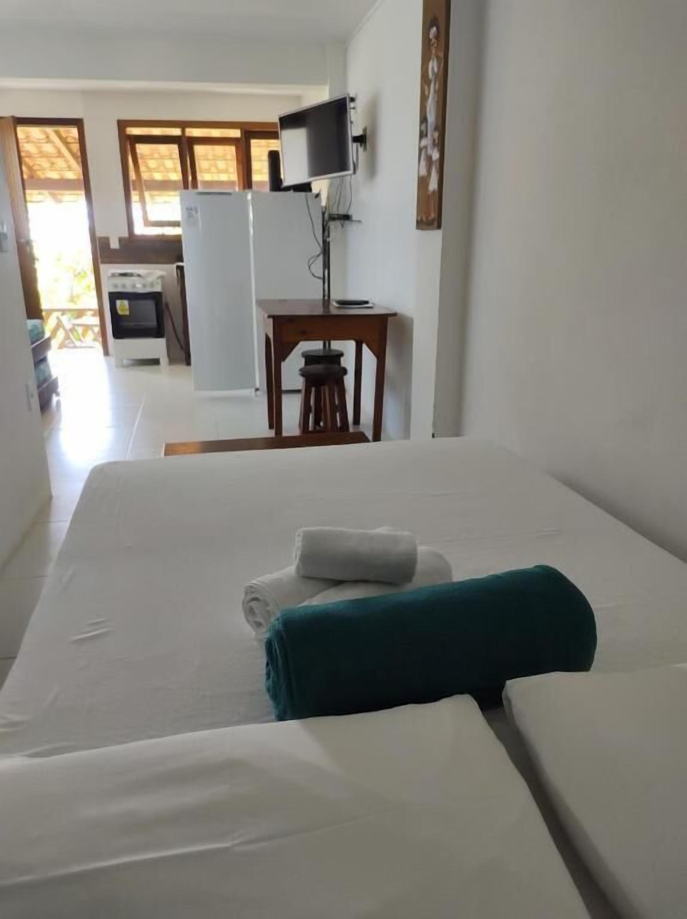 A hotel room with a bed, a TV, and a kitchenette in the background.