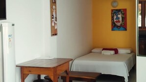Una habitación pequeña con una cama, una mesa y dos taburetes.