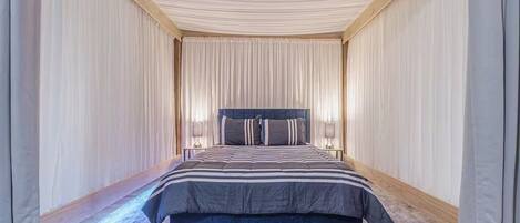 Un dormitorio con una cama grande, dos mesitas de noche y un cabecero.