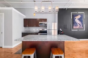 A modern kitchen with granite countertops, stainless steel appliances, and a central island with stools. - Casual corner (Detroit)