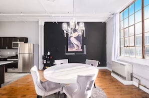 A modern kitchen with stainless steel appliances, a dining area with a round table and chairs, and a large window with a view. - Casual corner (Detroit)