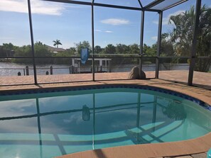 A swimming pool with a view of a body of water and surrounding greenery. - Luxury Waterfront Pool Home Minutes from Boca Grande and Englewood Beaches! (Port Charlotte)
