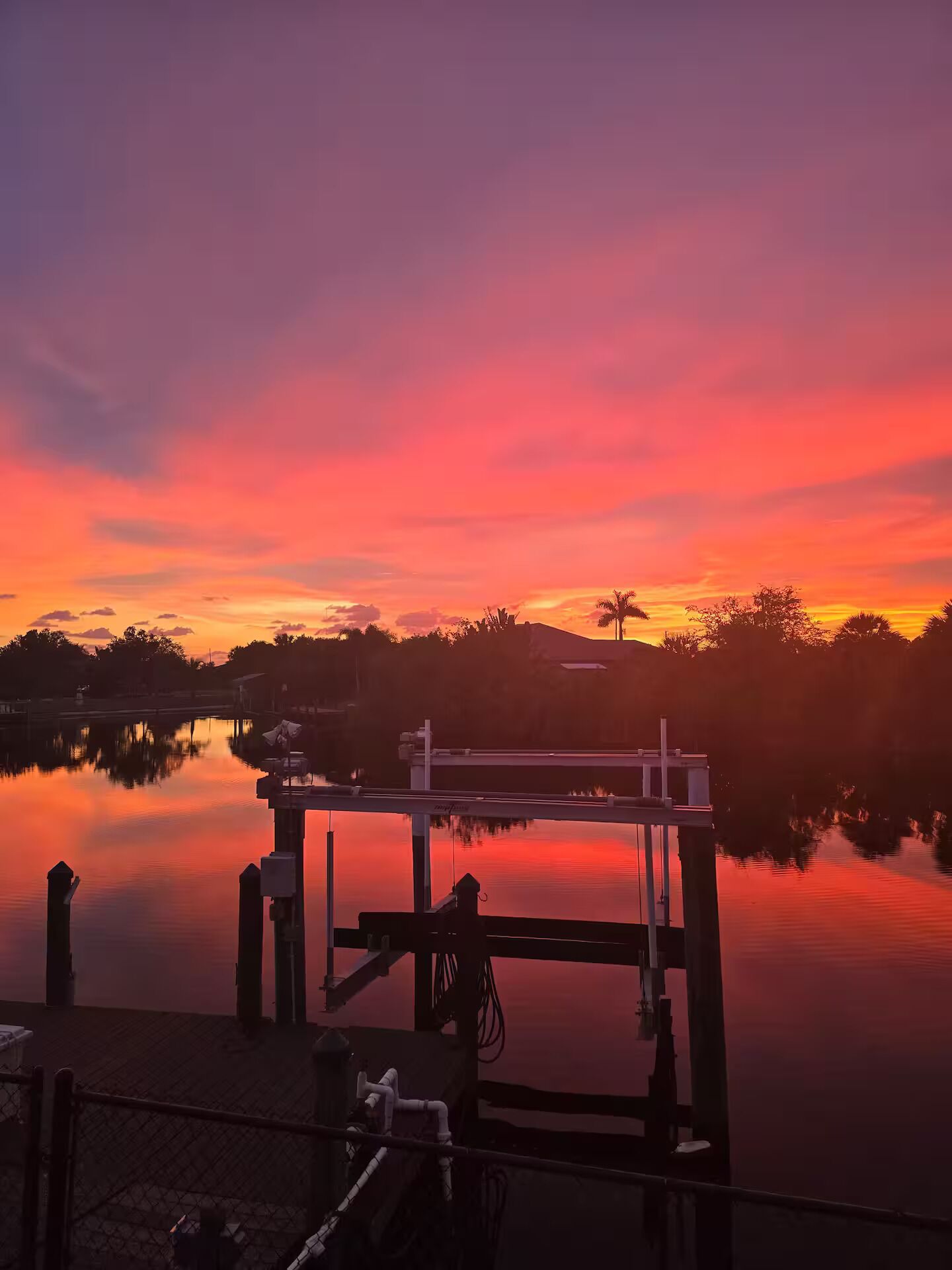 Un muelle con una superficie acuática tranquila que refleja el cielo al atardecer.