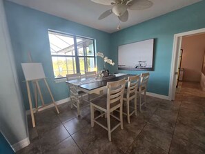 A dining area with a table, chairs, a ceiling fan, a window, and a painting on the wall. - Luxury Waterfront Pool Home Minutes from Boca Grande and Englewood Beaches! (Port Charlotte)