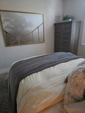 A bedroom with a bed, a painting, a wardrobe, and a plant. - Luxury Waterfront Pool Home Minutes from Boca Grande and Englewood Beaches! (Port Charlotte)