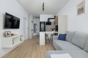 A modern living room with a flat-screen TV, a grey sofa, and a small coffee table. - Functional Apartment with Desk | Gym and Sauna (Katowice)