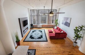 Ein großzügiges Wohnzimmer mit einem roten Sofa, einem gemusterten Teppich und einem Kamin.