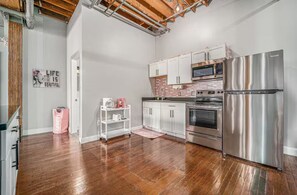 A modern kitchen with stainless steel appliances, white cabinetry, and a wooden floor.