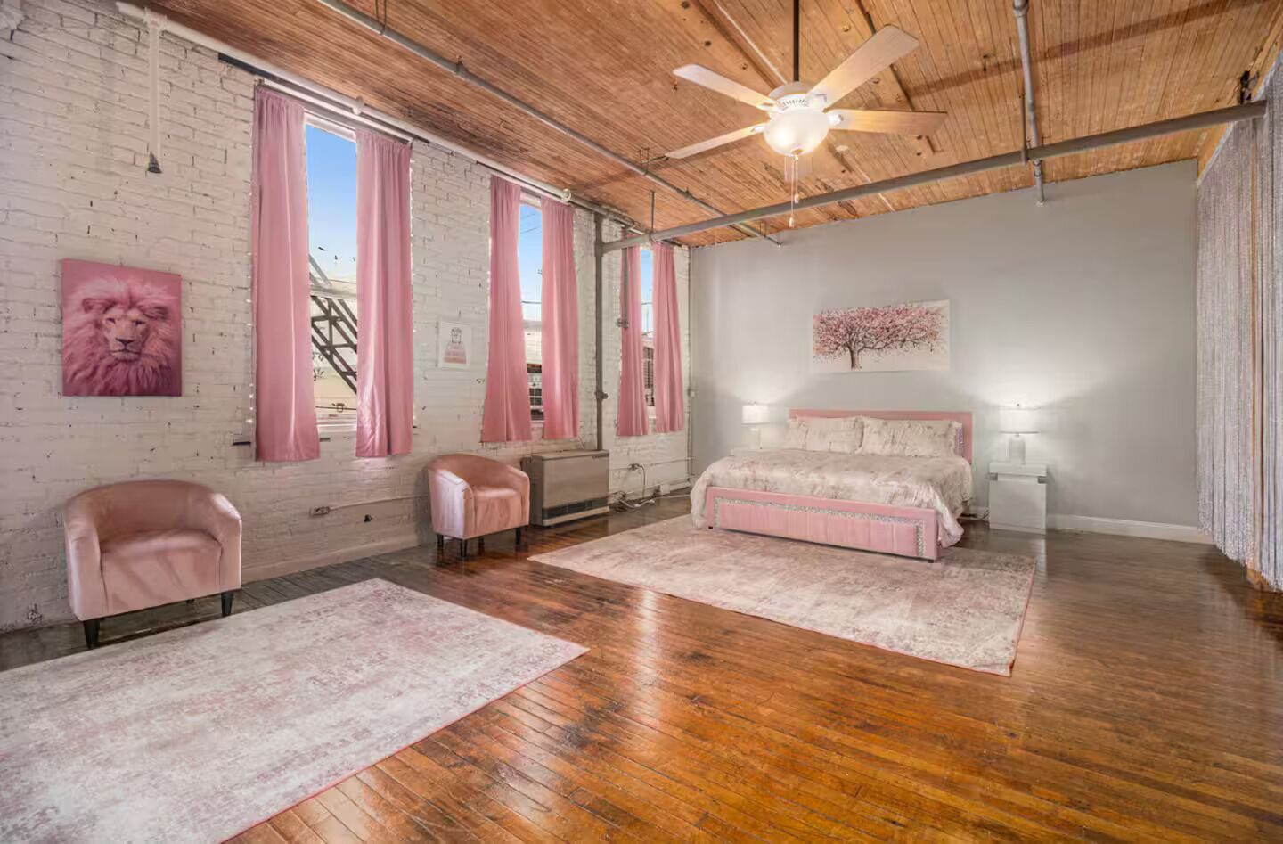 Une chambre à coucher avec un plafond en bois, un lit, une chaise et une fenêtre avec des rideaux.