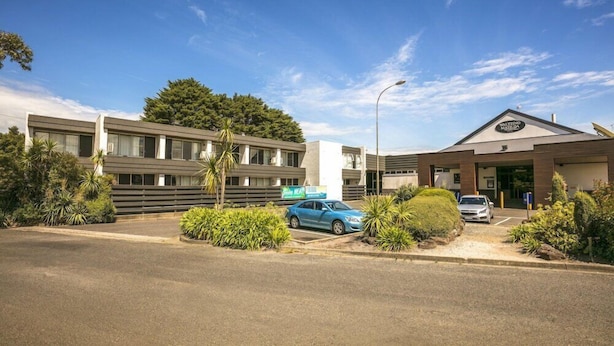 A hotel with a modern design, featuring a parking lot and a building with a sign. - Waltzing Matilda Hotel (Melbourne)