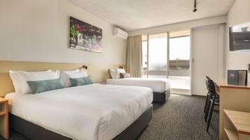 A hotel room with two beds, a desk, a chair, a television, and a large window.