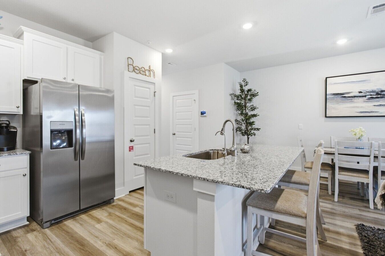 A modern kitchen with a stainless steel refrigerator, granite countertop, and a built-in sink.