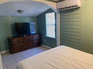 A bedroom with a bed, a dresser, a television, and a window with blinds. - Cozy 1BR Apartment Near Downtown Sarasota & Beaches, Pet-Friendly, Sleeps 3 (Sarasota)