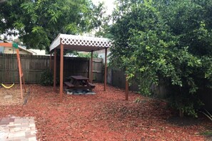 A backyard with a wooden swing set, a picnic table, and a covered seating area. - Cozy 1BR Apartment Near Downtown Sarasota & Beaches, Pet-Friendly, Sleeps 3 (Sarasota)