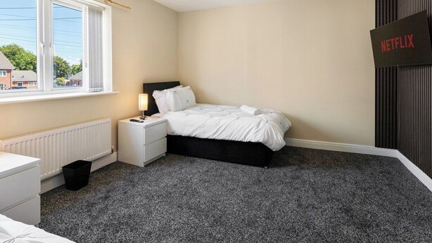 A bedroom with a bed, bedside table, lamp, and a sign for Netflix. - Cozy 4-Bed Birkenhead Home, Ideal for Contractors (Merseyside)