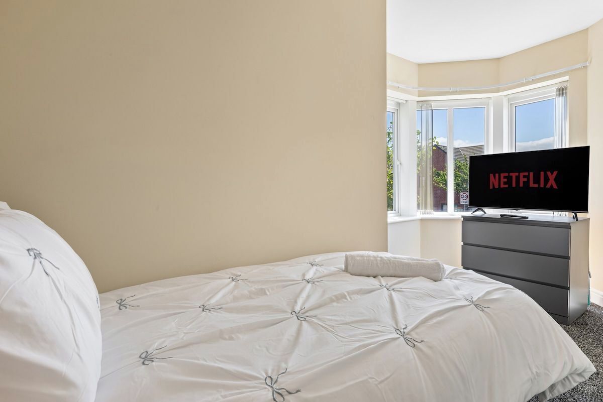 Quarto de hotel com cama, televisão sobre um suporte e janela com vista.