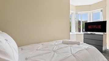 Quarto de hotel com cama, televisão sobre um suporte e janela com vista.