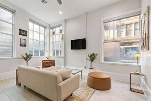 A modern living room with a sofa, ottoman, and large windows.
