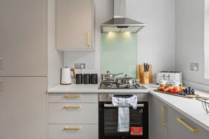 A modern kitchen with a built-in oven, a gas stove, and a stainless steel range hood. - Stylish 3BR Mellor House close to Old Trafford (Stretford)