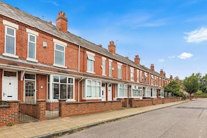 A row of terraced houses with a paved driveway and a clear sky. - Stylish 3BR Mellor House close to Old Trafford (Stretford)