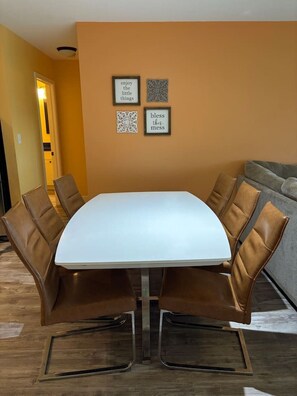 A dining area with a white table and brown leather chairs, framed by a wall with decorative items. - Private Paradise w/Hot Tub @ The SeaBird (Galveston)