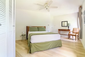 A bedroom with a bed, a desk, a chair, a ceiling fan, and a window with curtains. - Rum Fun Sun at Lantana No. 25 | Refreshed 1BR, 2 Pools, West Coast Barbados (St. James)