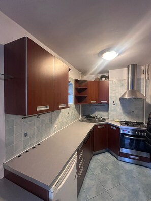 A modern kitchen with dark wooden cabinets, a stainless steel range hood, and a built-in oven. - Zelazna 2-bedroom apartment in City Center,Pet Friendly (Warszawa)