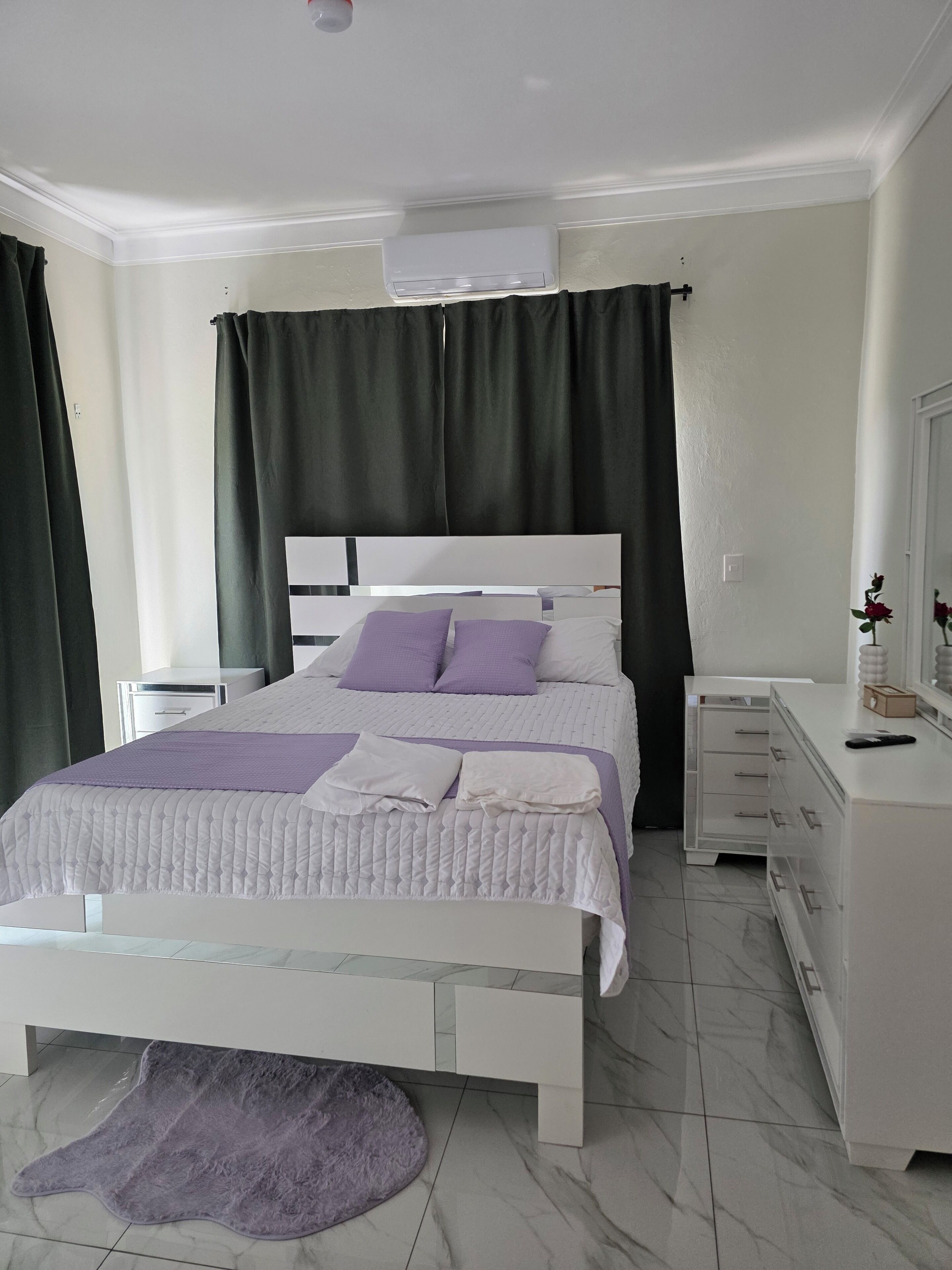 Un dormitorio moderno con cama, mesitas de noche, cómoda y espejo.