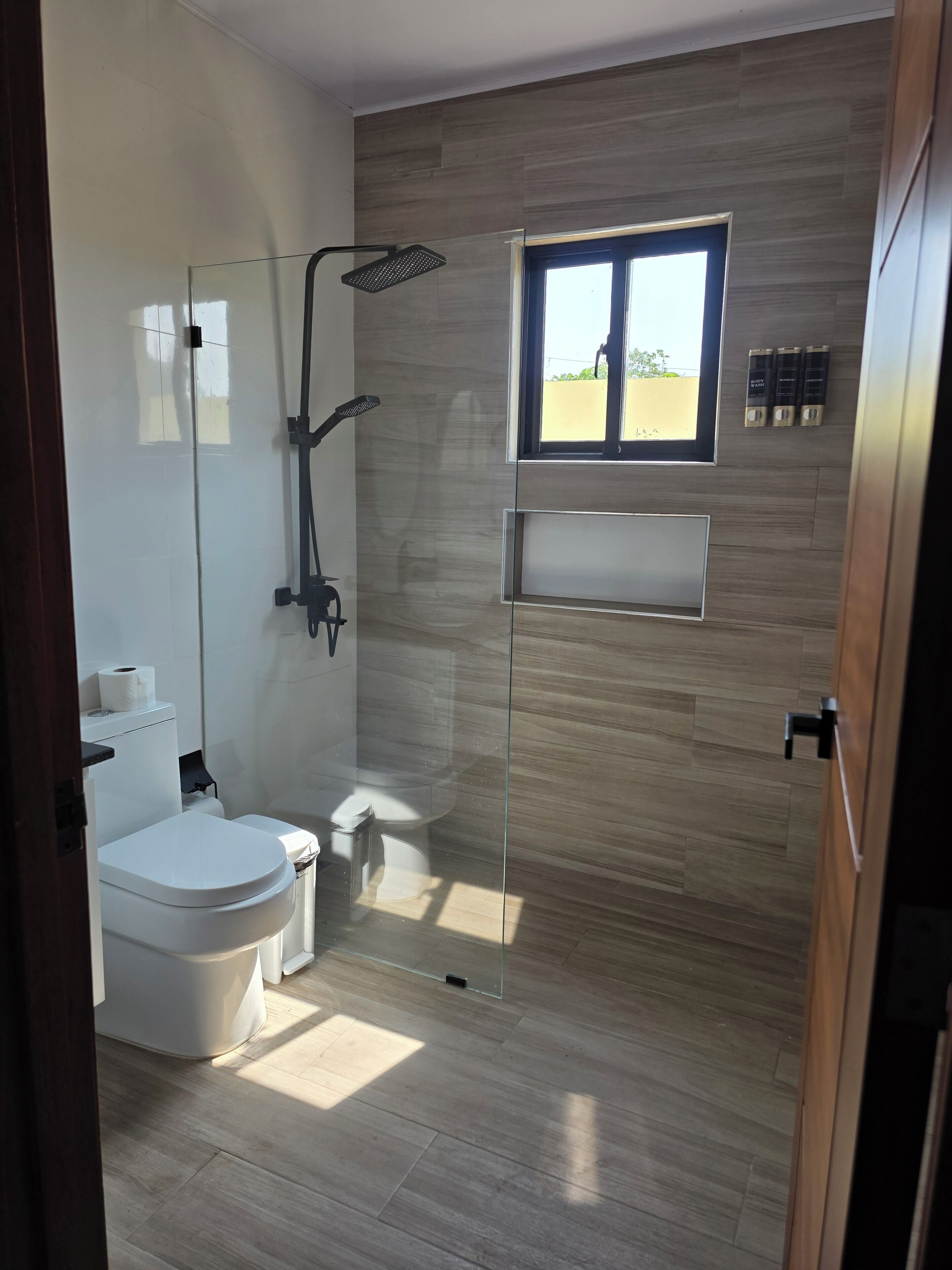 Un baño moderno con inodoro, ducha y ventana.