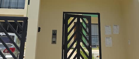 A multi-story building with a gated entrance, balconies, and a clear sky.