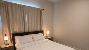 Un lit bien fait, avec du linge de lit blanc, deux tables de chevet avec des lampes, une tête de lit en bois et une grande fenêtre avec des rideaux.