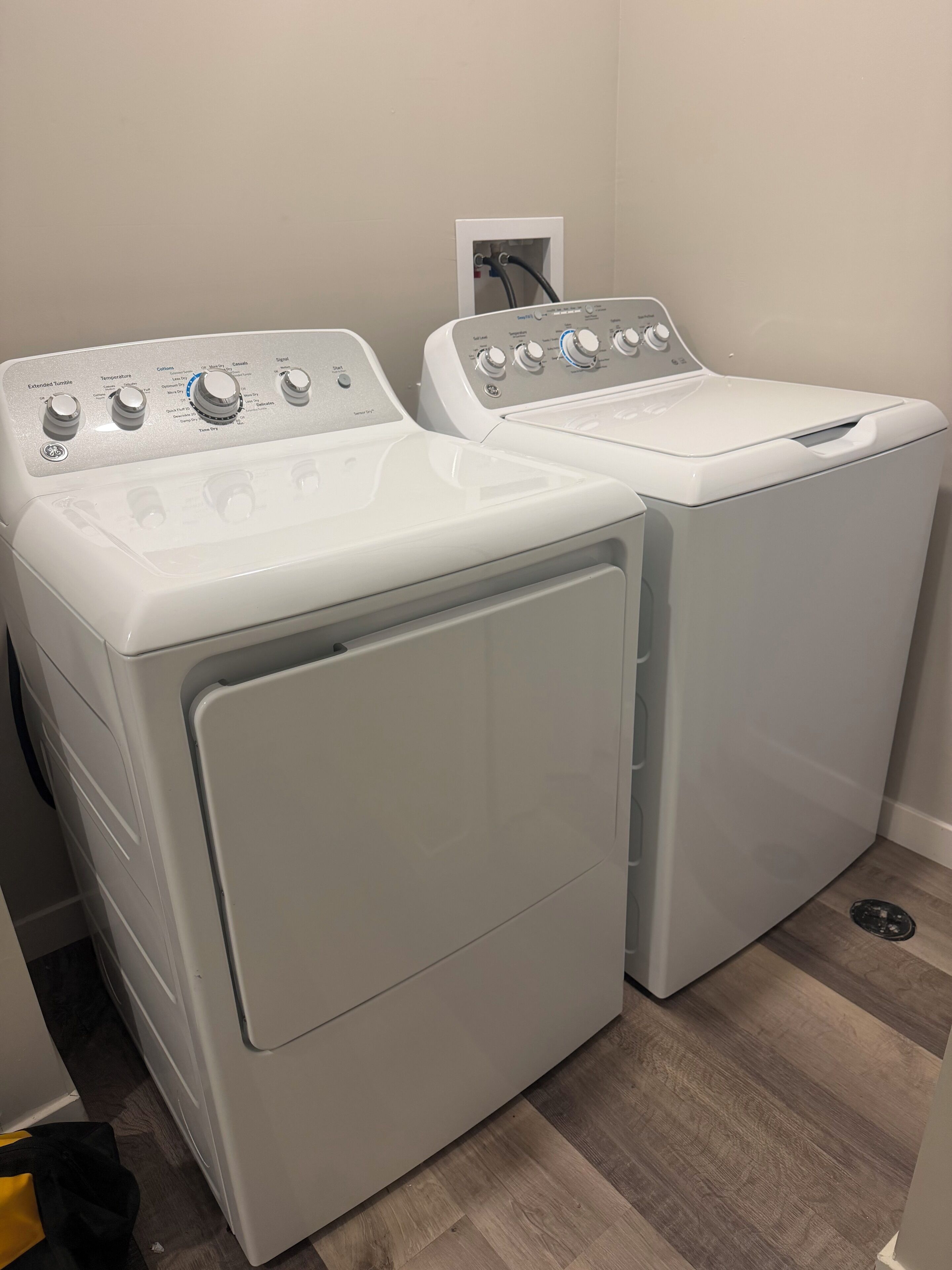 Two front-loading washing machines in a laundry room with a wooden floor.