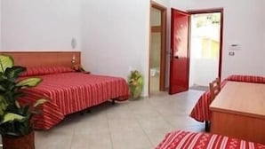 Una camera da letto con due letti, una testiera in legno, una pianta in vaso e una porta rossa.