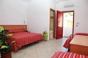 A bedroom with two beds, a wooden headboard, a potted plant, and a red door. - Luigiane B&B (Acquappesa)