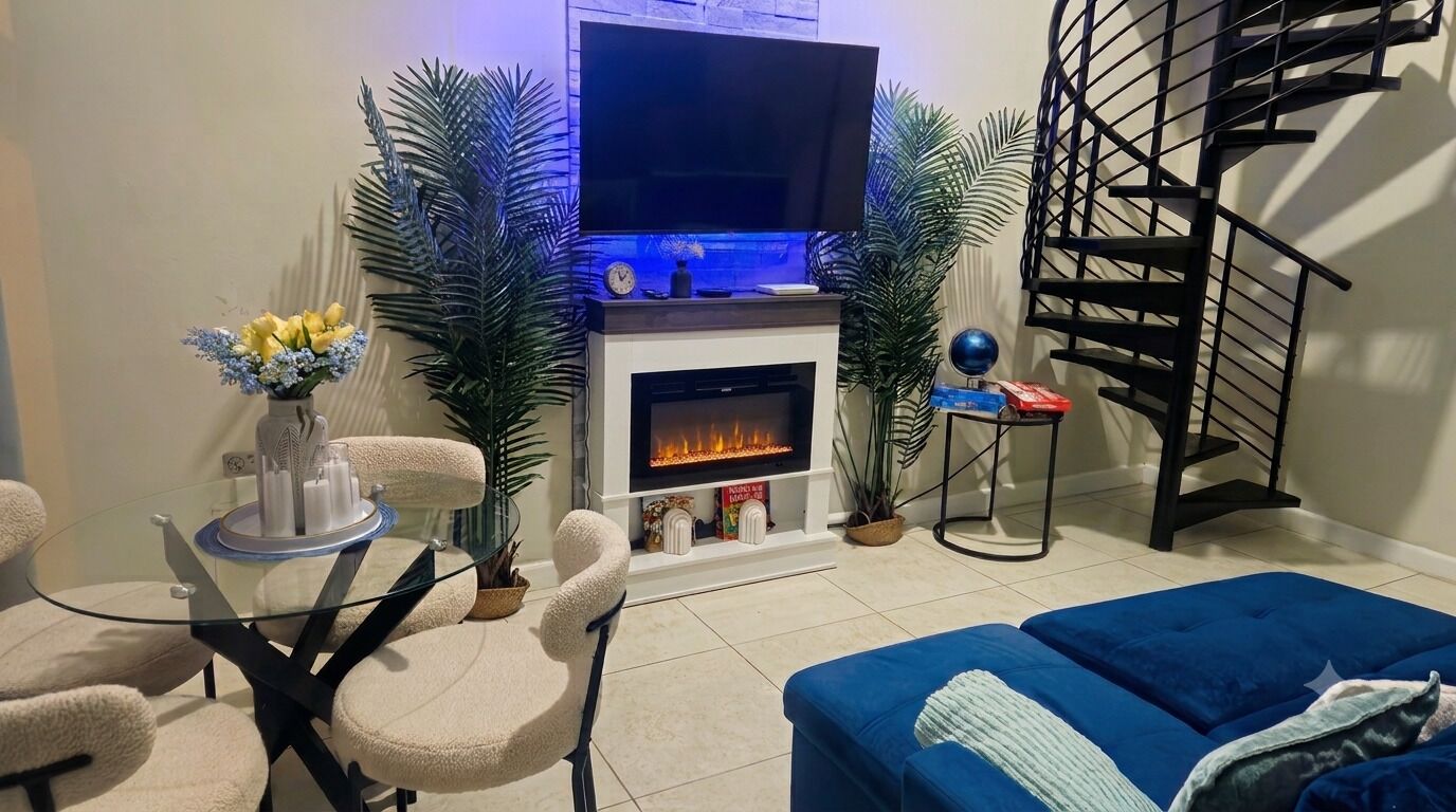 Uma sala de estar com lareira, um sofá, uma televisão e uma escada.