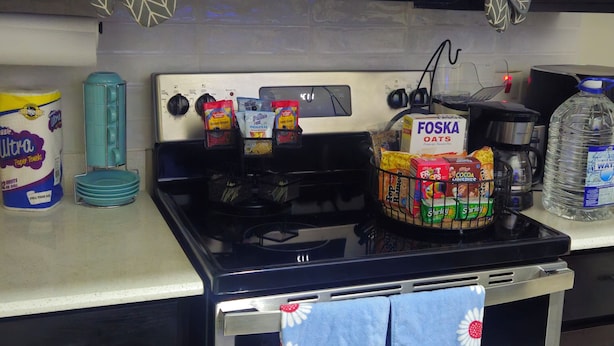 Una cocina con microondas, estufa y horno, con paños de cocina colgados de los mangos del horno.