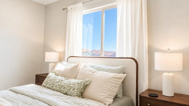 Una camera da letto con un letto, due comodini, una finestra con tende e vista sull'esterno.