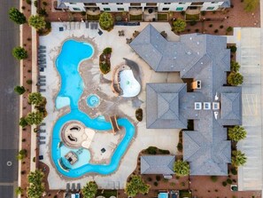 Eine Vogelperspektive auf ein Hotel mit Schwimmbad, mehreren Gebäuden und angelegten Grünflächen.
