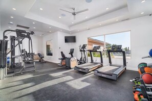 Ein Fitnessstudio mit Laufbändern, Crosstrainern und Gewichten.