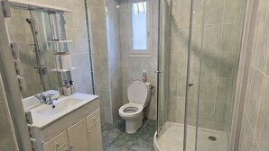 Et badeværelse med bruser, toilet og håndvask.