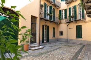 Ein Innenhof mit einem Gebäude, das Balkone, eine Tür und ein kleines Fenster aufweist.