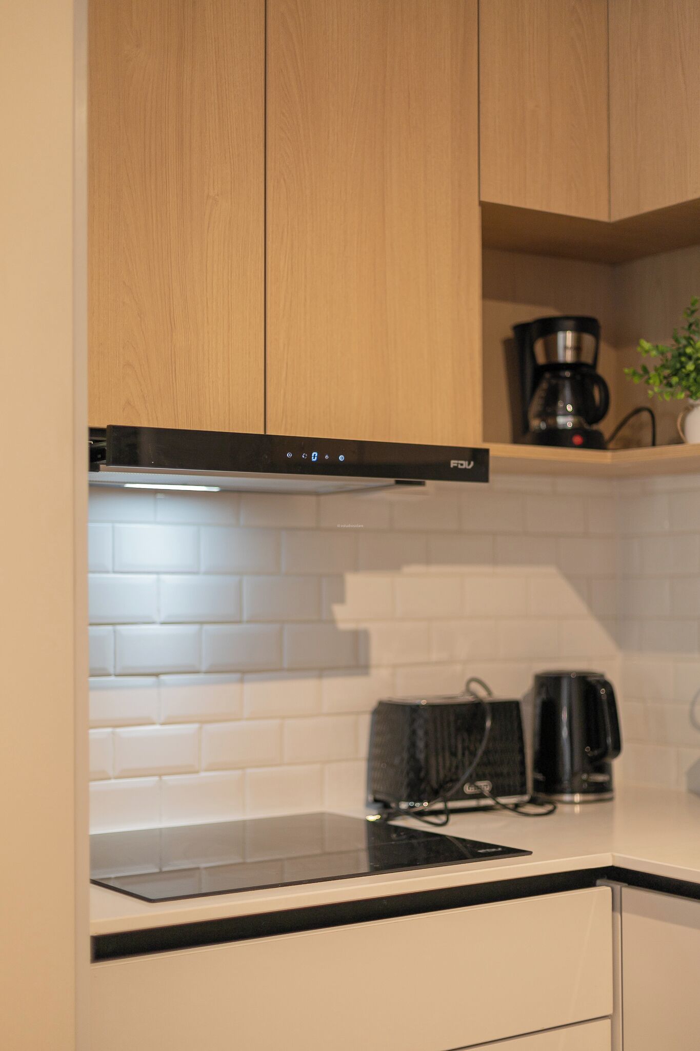 A kitchen with a black range hood, a coffee maker, and a kettle on the countertop.