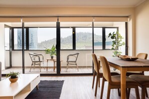 A modern interior with a dining area, large windows, and a view of a cityscape. - Vitacura Apartments by Andes STR (Las Condes)