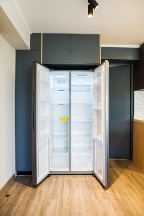 A modern kitchen with a built-in refrigerator, wooden flooring, and a dark-colored cabinet above the counter.