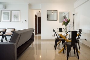 A modern living room with a sofa, a dining table with chairs, and a vase with flowers.